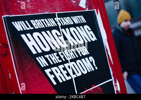 La gente cammina per un poster che chiede la solidarietà britannica con i manifestanti pro-democrazia a Hong Kong, presentati dal gruppo attivista "Fight for Freedom Stand with Hong Kong” su una cassetta telefonica a Whitehall a Londra, in Inghilterra, il 3 dicembre 2019. (Foto di David Cliff/NurPhoto) Foto Stock