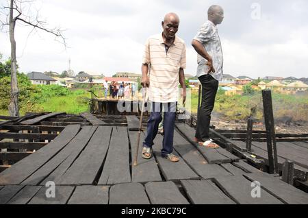 A old man walk pass the wooden-bridge in the community razed by fire, as fire rages from a ruptured oil pipeline, which was by oil thieves at Diamond Estate/Idowu Egba, Egbe-Idimu Local Council Development Area of Lagos, Nigeria commercial capital, on December 5, 2019. Another yet-to-be-identified victim, the three victims were having a bath in a stream in the area to cleanse themselves spiritually when the fire started and subsequently burned two of them to death. (Photo by Olukayode Jaiyeola/NurPhoto) Stock Photo