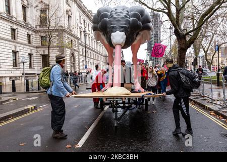 I membri dell'organizzazione ambientale Extension Rebellion protestano presso la Piazza del Parlamento a Londra, Inghilterra, il 6 dicembre 2019. L'organizzazione organizza la cosiddetta operazione Big Bird, dove i manifestanti marzo con una statua di un uccello che nasconde la sua testa in sabbia ha lo scopo di illustrare un atteggiamento dei politici verso l'emergenza ambientale. L’organizzazione protesta per esercitare pressioni sui politici prima delle elezioni generali nel Regno Unito. (Foto di Dominika Zarzycka/NurPhoto) Foto Stock