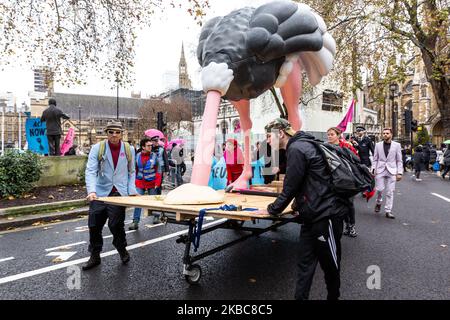 I membri dell'organizzazione ambientale Extension Rebellion protestano presso la Piazza del Parlamento a Londra, Inghilterra, il 6 dicembre 2019. L'organizzazione organizza la cosiddetta operazione Big Bird, dove i manifestanti marzo con una statua di un uccello che nasconde la sua testa in sabbia ha lo scopo di illustrare un atteggiamento dei politici verso l'emergenza ambientale. L’organizzazione protesta per esercitare pressioni sui politici prima delle elezioni generali nel Regno Unito. (Foto di Dominika Zarzycka/NurPhoto) Foto Stock