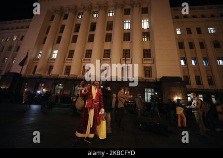 A man wearing a costume of Santa Claus walks past Presidential Office building as people wait for the results of Normandy format summit in Paris at a tent camp in front President Volodymyr Zelensky office in Kyiv, Ukraine, at the evening December 9, 2019 during a picket demanding 'no capitulation' to Russia ahead of a summit in Paris aimed at ending the hostilities between Ukraine and Russia. (Photo by Sergii Kharchenko/NurPhoto) Stock Photo