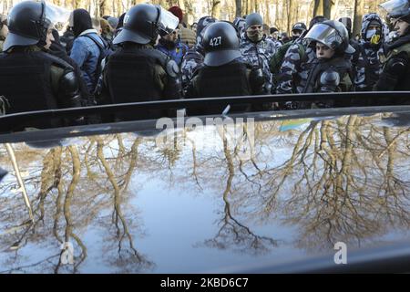 Activists of Ukrainian far-right National Militia movement wearing relevant clothes stand in front of the police officers during a protest of agricultural workers against land reform in Kyiv, Ukraine, December 17, 2019. Dozens of far-right activists clashed with the police in front of the Ukrainian Parliament as people peacefully protested against possible land market law passing by lawmakers of Verkhovna Rada. In November 2019, the parliament passed the first reading of a government bill 'On amending certain legislative acts of Ukraine concerning the turnover of agricultural land,' which will Stock Photo