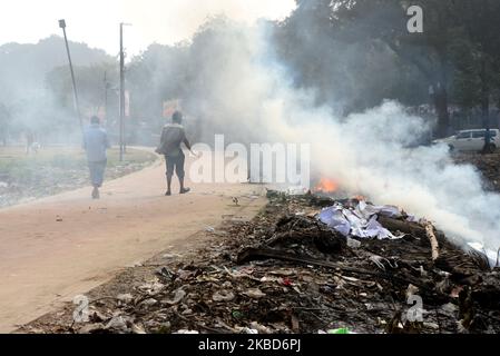 La gente che cammina come la spazzatura sta bruciando accanto ad una strada in un parco a Dhaka, Bangladesh, il 18 dicembre 2019. Il Bangladesh, uno dei paesi più densamente popolati del mondo, ha lottato per lungo tempo contro l’inquinamento atmosferico, mentre Dhaka continua ad essere tra le città più inquinate. Le principali fonti di inquinamento, secondo lo studio, sono i combustibili solidi per uso domestico, le polveri da costruzione, le centrali elettriche a carbone, la produzione di mattoni, i trasporti e le attrezzature diesel, tra gli altri. La qualità dell’aria in Asia è rimasta ostinatamente povera; soprattutto in Bangladesh, dove l’intera popolazione h Foto Stock