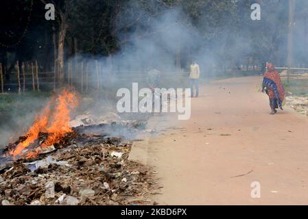 La gente che cammina come la spazzatura sta bruciando accanto ad una strada in un parco a Dhaka, Bangladesh, il 18 dicembre 2019. Il Bangladesh, uno dei paesi più densamente popolati del mondo, ha lottato per lungo tempo contro l’inquinamento atmosferico, mentre Dhaka continua ad essere tra le città più inquinate. Le principali fonti di inquinamento, secondo lo studio, sono i combustibili solidi per uso domestico, le polveri da costruzione, le centrali elettriche a carbone, la produzione di mattoni, i trasporti e le attrezzature diesel, tra gli altri. La qualità dell’aria in Asia è rimasta ostinatamente povera; soprattutto in Bangladesh, dove l’intera popolazione h Foto Stock