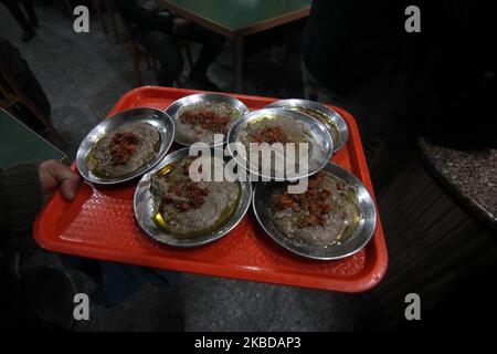 Un cameriere che serve Harisa ai clienti in una fredda mattinata a Srinagar, Kashmir il 21 dicembre, 2019.Harisa è una ricetta unica di montone vecchio di età preparata durante gli inverni in Kashmir.è disponibile principalmente nelle ore di mattina fatte di montone specialmente di sheep.The monton è cucinato in primo luogo sotto temperatura mite e tutte le ossa sono estratte per renderlo boneless.The monton è mescolato allora con farina di riso, Acqua e spezie varie e viene mescolato costantemente fino a diventare squashy.People per lo più gustare questo piatto con pane al forno. (Foto di Faisal Khan/NurPhoto) Foto Stock