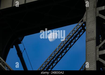 La luna attraversa il Williamsburg Bridge, un ponte sospeso a New York City attraverso l'East River, che collega la Lower East Manhattan con il quartiere di Williamsburg a Brooklyn, a Broadway. La Luna illuminante, satellite naturale della terra in orbita, come si vede nella fase gibbosa in declino, calendario lunare, con il 76% visibile. NYC, USA - 17 novembre 2019 (Foto di Nicolas Economou/NurPhoto) Foto Stock