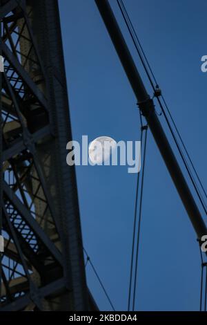 La luna attraversa il Williamsburg Bridge, un ponte sospeso a New York City attraverso l'East River, che collega la Lower East Manhattan con il quartiere di Williamsburg a Brooklyn, a Broadway. La Luna illuminante, satellite naturale della terra in orbita, come si vede nella fase gibbosa in declino, calendario lunare, con il 76% visibile. NYC, USA - 17 novembre 2019 (Foto di Nicolas Economou/NurPhoto) Foto Stock