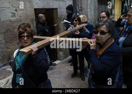 Un gruppo di pellegrini porta una croce di legno su Via dolorosa, una strada nella Città Vecchia di Gerusalemme, Israele, il 10 dicembre 2019. Questa strada è stata presa, tradizionalmente, come parte dell'itinerario che Cristo ha preso, portando la Croce, la via della sua crocifissione. (Foto di Joaquin Gomez Sastre/NurPhoto) Foto Stock