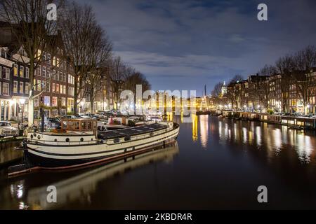I canali di Amsterdam come Amstel, con la tipica architettura tradizionale olandese, ospitano case illuminate e case galleggianti la sera e la notte con splendidi riflessi sull'acqua e luci della città, Olanda, Olanda. Amsterdam è un centro finanziario, ma anche una delle città più visitate d'Europa, che attrae milioni di turisti in tutto il mondo, con il turismo che svolge un ruolo significativo nell'economia locale nonostante le voci che si oppongono a questo sviluppo turistico. (Foto di Nicolas Economou/NurPhoto) Foto Stock