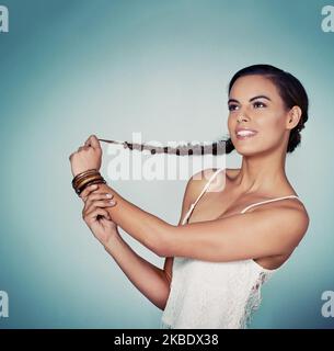 In questo modo i miei capelli cresceranno ancora più a lungo. Studio di una bella giovane donna che posa su uno sfondo verde. Foto Stock