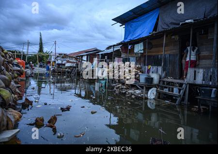 I residenti si spostano nelle loro case che sono allagate da inondazioni di marea o maree marine nel villaggio di Tompe, Distretto di Sirenja, Regency di Dongala, Provincia Centrale di Sulawesi, Indonesia il 12 gennaio 2020. Le inondazioni di marea che entrano nelle aree residenziali si verificano ogni 15 giorni a causa di una diminuzione della superficie terrestre fino a due metri a causa del terremoto di magnitudine 7,4 centrato nel villaggio il 28 settembre 2018 allora. I residenti locali sono costretti a fuggire in alto e tornare alle loro case dopo che l'acqua è diminuita. Questa condizione si è verificata da un anno e mezzo fa fino ad ora. (Foto di Basr Foto Stock