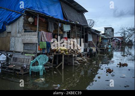 I residenti si spostano nelle loro case che sono allagate da inondazioni di marea o maree marine nel villaggio di Tompe, Distretto di Sirenja, Regency di Dongala, Provincia Centrale di Sulawesi, Indonesia il 12 gennaio 2020. Le inondazioni di marea che entrano nelle aree residenziali si verificano ogni 15 giorni a causa di una diminuzione della superficie terrestre fino a due metri a causa del terremoto di magnitudine 7,4 centrato nel villaggio il 28 settembre 2018 allora. I residenti locali sono costretti a fuggire in alto e tornare alle loro case dopo che l'acqua è diminuita. Questa condizione si è verificata da un anno e mezzo fa fino ad ora. (Foto di Basr Foto Stock