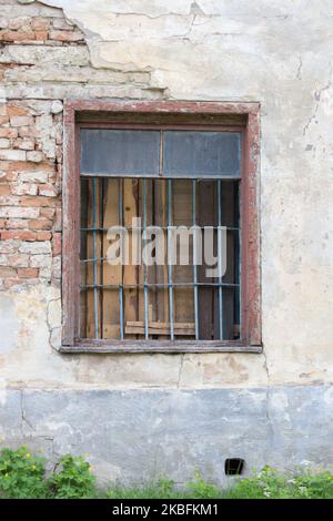 Vecchia finestra in pietra con barre e filo spinato su di essa Foto Stock