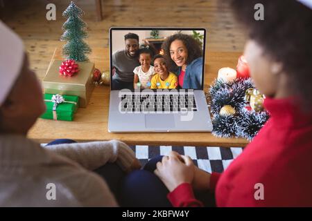 Coppia afro-americana con cappelli di babbo natale videochiamata con famiglia afro-americana Foto Stock