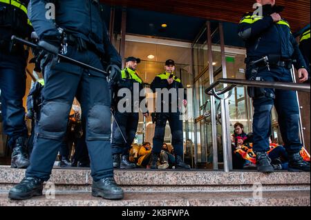 Gli attivisti DELLA XR sono incollati alle porte di cristallo della sede della Shell, all'Aia, durante un'azione contro la compagnia petrolifera, il 31st gennaio 2020. (Foto di Romy Arroyo Fernandez/NurPhoto) Foto Stock