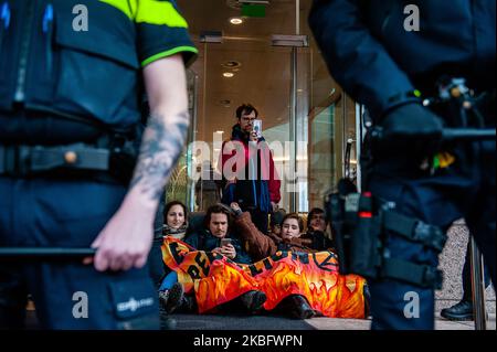 Gli attivisti DELLA XR sono incollati alle porte di cristallo della sede della Shell, all'Aia, durante un'azione contro la compagnia petrolifera, il 31st gennaio 2020. (Foto di Romy Arroyo Fernandez/NurPhoto) Foto Stock