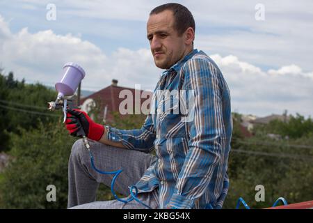 marito pittore che riposa sul tetto dopo la pittura Foto Stock