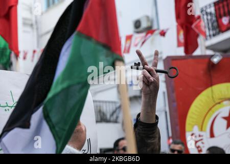 Un manifestante tunisino solleva una chiave mentre fa il segno della vittoria mentre una bandiera della Palestina viene sventolata durante un raduno popolare che si tiene di fronte alla sede della Tunisian General Labor Union (UGTT) per protestare contro il piano di pace per il Medio Oriente chiamato 'il 'sigillo Del secolo' che è stato svelato dal presidente degli Stati Uniti Donald Trump, a Tunisi, Tunisia il 05 febbraio 2020. (Foto di Chardy ben Ibrahim/NurPhoto) Foto Stock