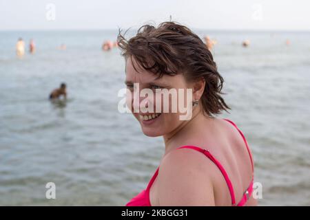 girando la testa la donna sorrise al mare Foto Stock