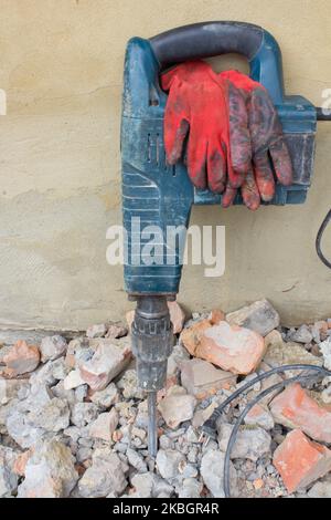 punzonatrice elettrica per utensili a mano su una pietra vicino al muro Foto Stock