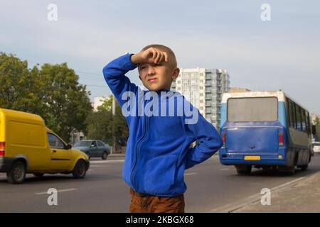 il ragazzo scappò dalla casa e aspettava l'autobus vicino alla strada Foto Stock