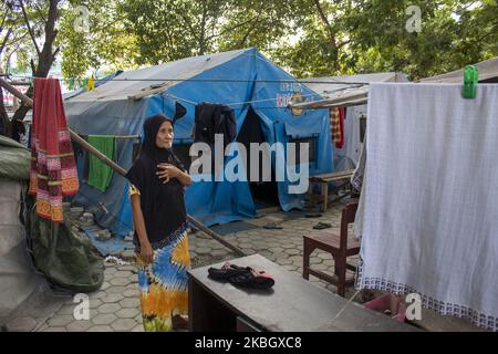 Una madre sopravvissuta al disastro è attiva di fronte alla sua tenda di emergenza presso il rifugio della moschea di Agung a Palu, Sulawesi centrale, Indonesia il 13 febbraio 2020. Centinaia di vittime di disastri che ancora sopravvivono nelle tende di emergenza hanno causato fino a un anno e mezzo di disastri di terremoto, tsunami e liquefazione nei distretti di Palu, Sigi e Dongala. Non hanno ricevuto assistenza di sicurezza sociale del valore di Rp 10.000 a persona al giorno per due mesi. Inoltre non sanno se otterranno un riparo temporaneo o permanente dopo che le loro case sono state distrutte dal disastro del 28 settembre 2018. (Pho Foto Stock