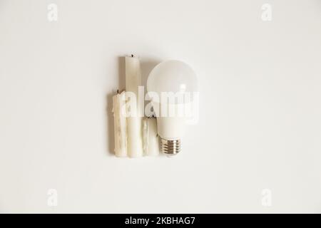 Lampadina a LED e candele su sfondo bianco, scelta di elettricità e risparmio, senza luce Foto Stock