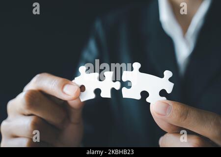 La donna di affari sta provando a collegare il pezzo del puzzle della coppia. Simbolo di associazione e connessione. Concetto di strategia aziendale Foto Stock