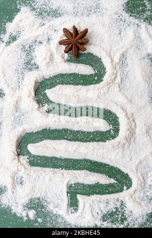 Un albero di Natale dipinto di farina come da neve con una stella secca di anice su sfondo verde. Cucina di Natale: Abete fatto di quattro, ingredi Foto Stock