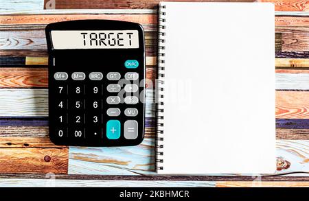 The word TARGET is written on a calculator. Top view of desktop and notepad. Finance or business concept. Stock Photo