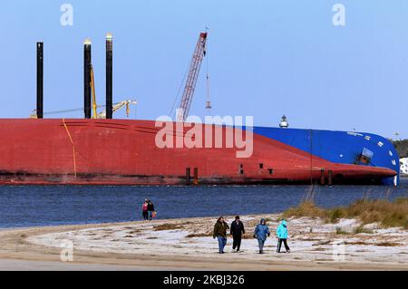 Le persone camminano sulla spiaggia vicino alla nave da carico Golden Ray il 27 febbraio 2020 a Jekyll Island, Georgia. In circa un mese, un'azienda di recupero comincerà a tagliare la nave in otto segmenti che possono essere sollevati dall'acqua e rimossi da una chiatta. Il vettore, caricato con 4200 nuove auto, si è catturato a St. Simons Island Sound il 8 settembre 2019 mentre stava lasciando il porto di Brunswick. (Foto di Paul Hennessy/NurPhoto) Foto Stock