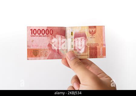 Semarang, Indonesia - 4 novembre 2022: Una mano tiene un denaro di Rupiah 100.000. Foto Stock