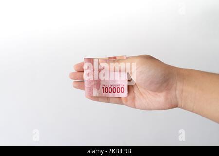 Semarang, Indonesia - 4 novembre 2022: Una mano tiene un denaro di Rupiah 100.000. Foto Stock