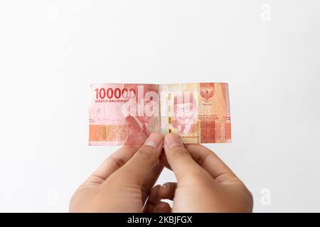 Semarang, Indonesia - 4 novembre 2022: Una mano tiene un denaro di Rupiah 100.000. Foto Stock