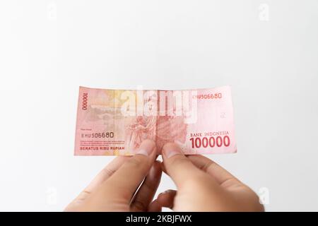 Semarang, Indonesia - 4 novembre 2022: Una mano tiene un denaro di Rupiah 100.000. Foto Stock