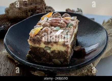 Crostini di torta al formaggio di zucca speziata fatti in casa glassa decorata con noci pecan e pistacchio affettato in piazze servito su piatto di ceramica. Foto Stock