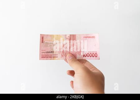 Semarang, Indonesia - 4 novembre 2022: Una mano tiene un denaro di Rupiah 100.000. Foto Stock