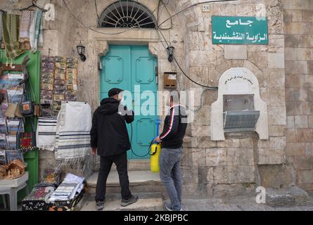 Due uomini spruzzano gli ingressi di un edificio lungo Via dolorosa, un percorso processionale nella Città Vecchia di Gerusalemme, che si ritiene sia il sentiero che Gesù ha percorso verso la sua crocifissione. Il Ministero della Salute di Israele ha appena annunciato che altre tre persone sono state diagnosticate con coronavirus portando il totale a 42 israeliani e 25 palestinesi testati positivi per coronavirus. Migliaia di persone sono ancora messe in isolamento e Israele può espandere la quarantena del coronavirus ai visitatori di tutti i paesi. Lunedì 9 marzo 2020 a Gerusalemme, Israele. (Foto di Artur Widak/NurPhoto) Foto Stock