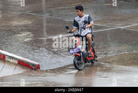 SAMUT PRAKAN, THAILANDIA, ottobre 03 2022, Un uomo guida uno scooter elettrico sotto la pioggia Foto Stock