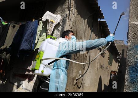 Volontari palestinesi spruzzano disinfettante in una strada nel campo profughi di al-Shati a Gaza City il 16 marzo 2020, durante una campagna di Hamas per arginare una nuova epidemia di coronavirus. – Il movimento islamico Hamas, che governa la striscia di Gaza assediata, ha compiuto l’insolito passo di chiudere i confini con Israele e Egitto come precauzione contro il virus. Finora non vi sono casi documentati di COVID-19 nell'enclave. (Foto di Majdi Fathi/NurPhoto) Foto Stock