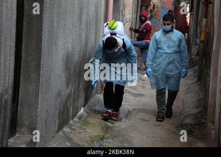 Volontari palestinesi spruzzano disinfettante in una strada nel campo profughi di al-Shati a Gaza City il 16 marzo 2020, durante una campagna di Hamas per arginare una nuova epidemia di coronavirus. – Il movimento islamico Hamas, che governa la striscia di Gaza assediata, ha compiuto l’insolito passo di chiudere i confini con Israele e Egitto come precauzione contro il virus. Finora non vi sono casi documentati di COVID-19 nell'enclave. (Foto di Majdi Fathi/NurPhoto) Foto Stock