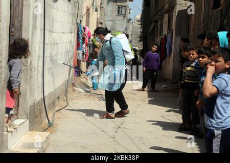 Volontari palestinesi spruzzano disinfettante in una strada nel campo profughi di al-Shati a Gaza City il 16 marzo 2020, durante una campagna di Hamas per arginare una nuova epidemia di coronavirus. – Il movimento islamico Hamas, che governa la striscia di Gaza assediata, ha compiuto l’insolito passo di chiudere i confini con Israele e Egitto come precauzione contro il virus. Finora non vi sono casi documentati di COVID-19 nell'enclave. (Foto di Majdi Fathi/NurPhoto) Foto Stock