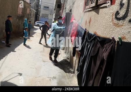 Volontari palestinesi spruzzano disinfettante in una strada nel campo profughi di al-Shati a Gaza City il 16 marzo 2020, durante una campagna di Hamas per arginare una nuova epidemia di coronavirus. – Il movimento islamico Hamas, che governa la striscia di Gaza assediata, ha compiuto l’insolito passo di chiudere i confini con Israele e Egitto come precauzione contro il virus. Finora non vi sono casi documentati di COVID-19 nell'enclave. (Foto di Majdi Fathi/NurPhoto) Foto Stock