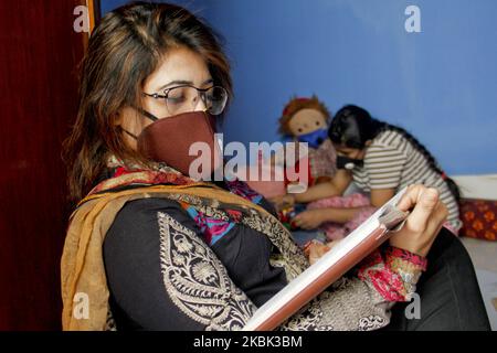 Una donna che indossa una maschera facciale per prevenire il coronavirus legge un libro il 16 marzo 2020 a Dhaka, Bangladesh. A causa della minaccia del virus Corona (COVID - 19) l'autorità del Bangladesh è già stata chiusa tutte le istituzioni educative e tutti i porti. La gente si sta facendo prendere dal panico, anche se lentamente. Una famiglia che soggiorna a casa con maschere. I bambini hanno anche mascherato le loro bambole mentre giocano a fianco della loro casa. (Foto di Khandaker Azizur Rahman Sumon/NurPhoto) Foto Stock