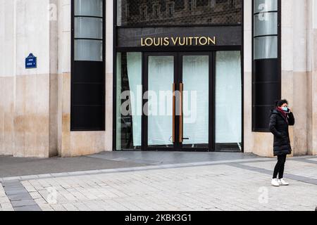 Una donna indossa una maschera di fronte al negozio chiuso Louis Vuitton il 16 marzo 2020 a Parigi, Francia. La Francia attende stasera l'intervento del presidente Emmanuel Macron su un possibile confinamento, blocco, contenimento della popolazione francese contro la propagazione del Coronavirus (COVID-19). Questa mattina a Parigi le strade erano quasi vuote, il negozio era chiuso, come le galeries Lafayette, Cartier, sul viale Champs Elysees, e i ristoranti, come il ristorante Fouquet's. (Foto di Jerome Gilles/NurPhoto) Foto Stock