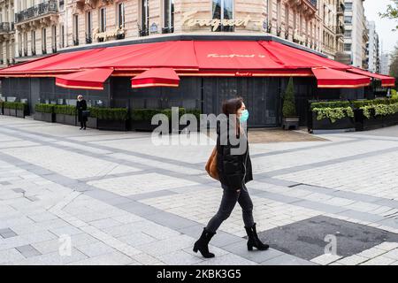 Una donna indossa una maschera di fronte al ristorante chiuso il 16 marzo 2020 a Parigi, Francia. La Francia attende stasera l'intervento del presidente Emmanuel Macron su un possibile confinamento, blocco, contenimento della popolazione francese contro la propagazione del Coronavirus (COVID-19). Questa mattina a Parigi le strade erano quasi vuote, il negozio era chiuso, come le galeries Lafayette, Cartier, sul viale Champs Elysees, e i ristoranti, come il ristorante Fouquet's. (Foto di Jerome Gilles/NurPhoto) Foto Stock