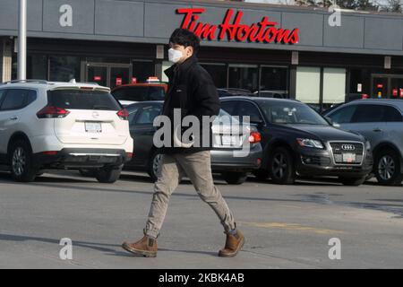 L'uomo che indossa una maschera facciale per proteggerlo dal romanzo coronavirus (COVID-19) passa davanti a una caffetteria Tim Hortons a Toronto, Ontario, Canada il 16 marzo 2020. Tim Hortons ha annunciato che chiuderà tutti i posti a sedere della sala da pranzo in mezzo alla crescente epidemia di COVID-19. Ciò viene come la provincia di Ontario ha annunciato ieri che sta chiudendo tutte le scuole, le biblioteche, le cure diurne e i centri comunitari per rallentare la diffusione di COVID-19. La città di Toronto e la città di Mississauga hanno annunciato che si ferma anche il servizio di ristorazione presso ristoranti e bar e che chiude i cinema. (Foto di Cre Foto Stock