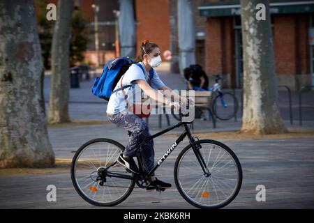 A young woman rides with a face mask. For the 2nd day, French people are on lockdown. On Monday March 16th, French President Macron announced that all people will be on lockdown due to the Covid-19 coronavirus pandemic. In Toulouse as elsewhere in France, all shops 'non essentials' were closed until further notice. Police patrols the streets to check people outside. People must have a permit to move around. As the Covid-19 coronavirus spreads across France, President Macron announced the closing down of all schools, highchools, universities to try to contain the spread of the coronavirus on Ma Stock Photo