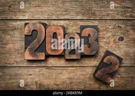 Change from year 2022 to 2023 written with vintage letterpress printing blocks on rustic wood background Stock Photo