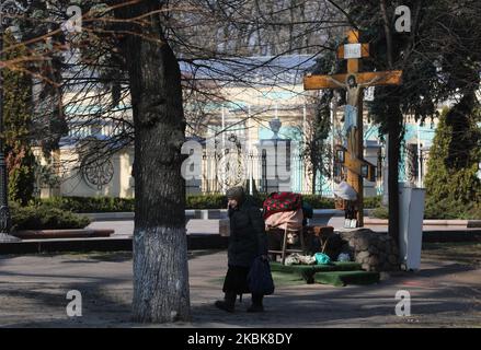 Una donna anziana cammina vicino alla crocifissione fissata dai fedeli del Patriarcato di Mosca della Chiesa Ortodossa di fronte al Parlamento ucraino a Kyiv, Ucraina, 19 marzo 2020. 26 casi di COVID-19 sono stati confermati in laboratorio in Ucraina, 3 dei quali erano letali. (Foto di Sergii Kharchenko/NurPhoto) Foto Stock